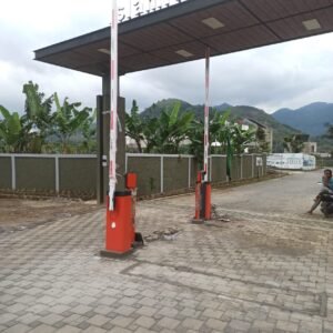 Dua unit palang parkir otomatis (barrier gate) warna oranye hitam untuk akses masuk keluar perumahan dengan sistem kartu RFID yang sedang diinstalasi